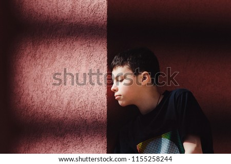 Teenage boy on a street in a big city next to a high-rise building alone. concept of a teenager life. portrait on brick wall background close up