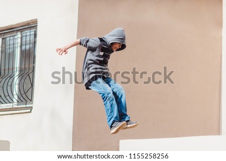 Teenage boy in the hood on a street in a big city next to a high-rise building alone. concept of a teenager parkour life. parkour jump portrait on the street in the big city close up