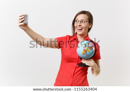 Smiling business teacher woman in red shirt holding mobile phone and doing taking selfie shot with globe isolated on white background. Education teaching in high school university concept. Copy space