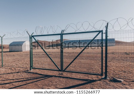 military hangar in the desert behind barbed wire