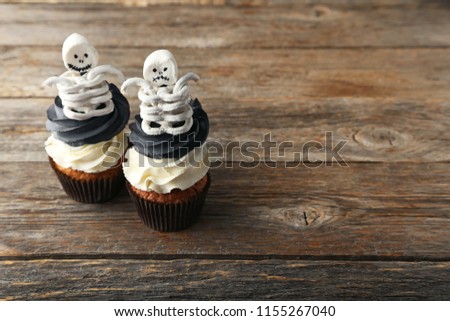 Halloween cupcakes with skeletons on grey wooden table