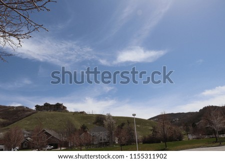 A blue sky with white clouds and a mansion on the hill in the distance