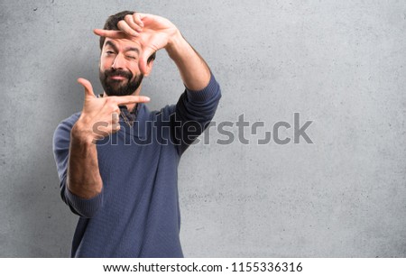 Handsome brunette man with beard focusing with his fingers on textured background