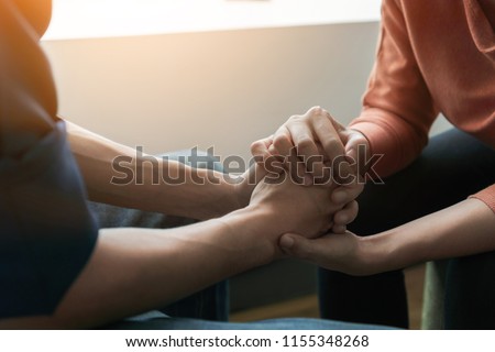 PTSD Mental health concept, Psychologist sitting and touch hand young depressed asian man for encouragement near window with low light environment.Selective focus. Royalty-Free Stock Photo #1155348268