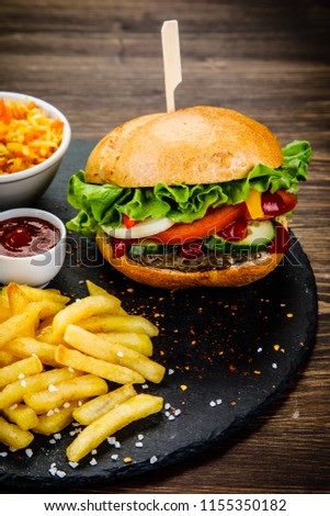 Tasty burger with chips served on stone plate 