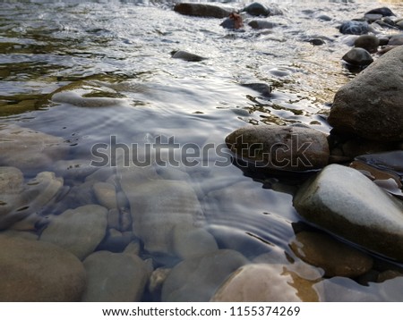 sea stones under blue water. Background of small multicolored stones lying under water.