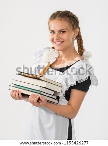Schoolgirl in school uniform, a stack of books in hands. beautiful playful teenagers in a festive dress back to school on a white background. cheerful schoolgirl. emotion of joy. successful learning
