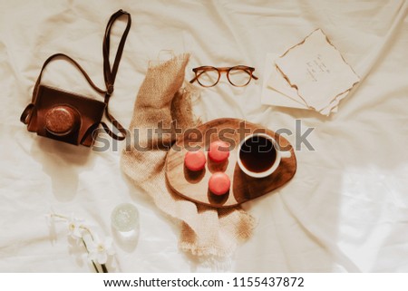 Trendy flat lay with pink macaroons cakes, cup of coffee, accessories, photo camera, glasses and retro cards. Lifestyle concept.