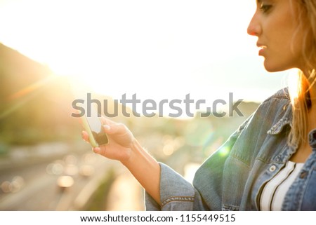 girl taking pictures of a landscape, close-up of a phone in her hand at sunset
