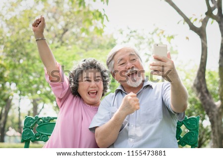 elderly people lifestyles and communication technology. Happy grandparent using tablet video call and talking with family in the park.