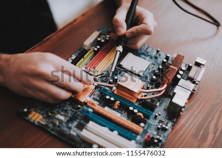 Close up. Young Man Repairing Motherboard from PC. Repair Shop. Worker with Tools. Computer Hardware. Magnifying Glass. Soldering Iron. Digital Device. Laptop on Desk. Electronic Devices Concept. Royalty-Free Stock Photo #1155476032