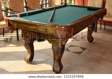 Beautiful photo of stylish pool table with a cue and billiard balls on a nice patio. Snooker 