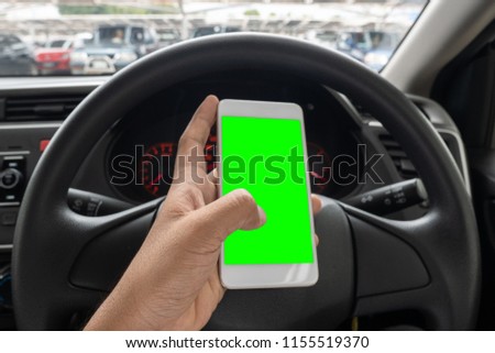 Close up hand man using smartphone with green screen driving car.