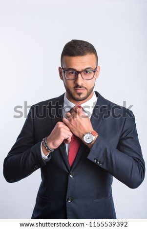 Handsome business man dressed in suit and eyeglass and fixes his necktie