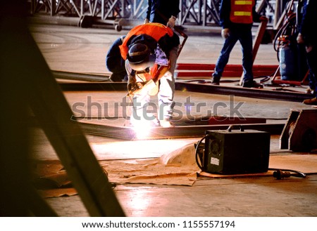 Construction worker welding a steel beam on a construction site.Worker welding with full protection mask,glove,shoes for safety.