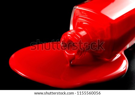 Women beauty products, luxury fashion and makeup concept with close up on a dropped bottle of red nail polish sitting in a pool of spilled red liquid on black background with dramatic lighting