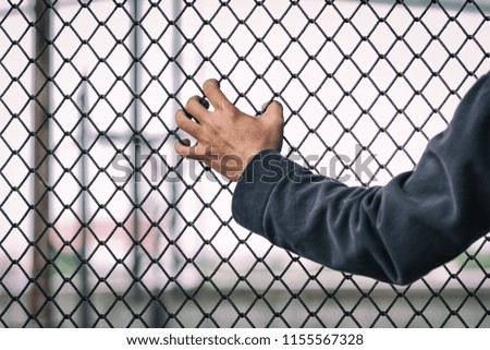 close up man's hand is caught on a metal fence.