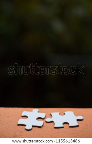 Two white paper jigsaw puzzles.