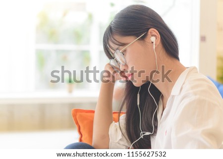 Asian high school teenager relaxing in library reading book and listening music