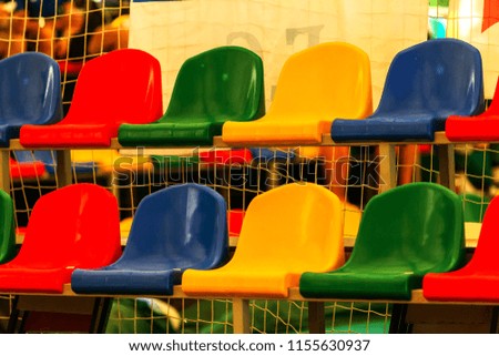 Multicolored Empty plastic chairs in the stands of the stadium. Many empty seats for spectators in the stands. Empty plastic chairs for football fans in the gym. Bright colorful seats for stadium fans