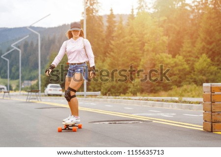 Young girl longboarding downhill on the hillside road