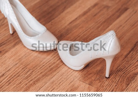 Beautiful white shoes of the bride. Bride's shoes are on the wooden floor.
