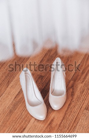 Beautiful white shoes of the bride. Bride's shoes are on the wooden floor under the dress.