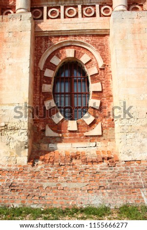 A fragment of an old brick wall with oval arch window guard - Russia, Mozhaisk Kremlin, region landmark Novo-Nikolsky Cathedral on a summer day