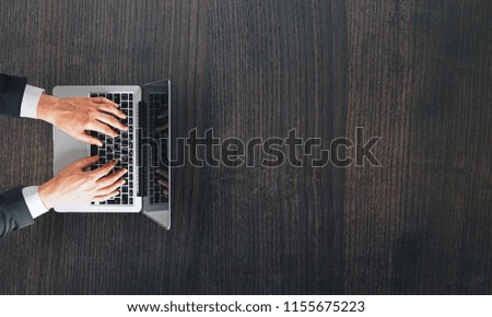 Top view of hands using laptop on wooden desk with copy space. Communication and technology concept 