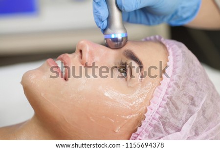 Hardware cosmetology. Closeup picture of happy young woman getting rf lifting procedure in a beauty parlour. Radio lifting.