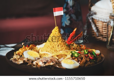 Traditional Indonesian Cuisine Nasi Tumpeng for Independence Celebration with Flag. Tumpeng is a cone-shaped rice dish like mountain with meats usually eat as breakfast or lunch
 Royalty-Free Stock Photo #1155710650