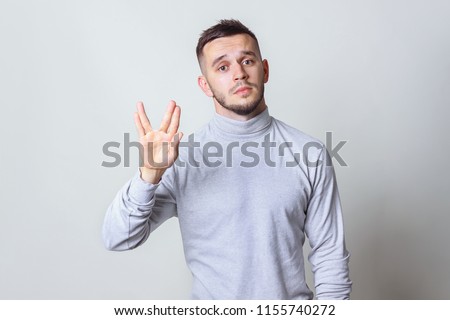 Geek saluting concept. Bristle men in white turtleneck shirt welcomes fans of fiction films Vulcan greeting on grey background copy space