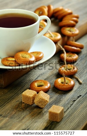 Cup of tea and small bagels with poppy seeds on a wooden table.