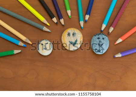 Painting and playing with stones and colorful pencils on the wooden table for children’s art activities in preschool or nursery.
