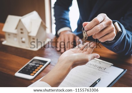 Real estate agent Sales manager holding filing keys to customer after signing rental lease contract of sale purchase agreement, concerning mortgage loan offer for and house insurance. Royalty-Free Stock Photo #1155763306