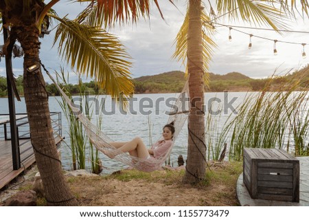 Asian woman relaxing in the hammock on tropical beach. Happy female with holiday.
