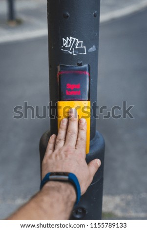 Human hand pushing button at pedestrian crossing saying "Signal coming"
