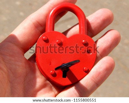    A wedding lock in the form of a heart is held in hands                            