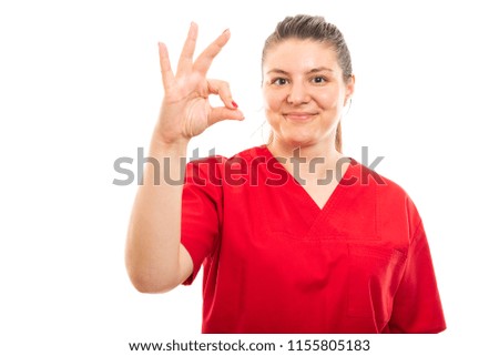 Portrait of young medical nurse wearing red scrub showing okay gesture isolated on white background with copyspace advertising area