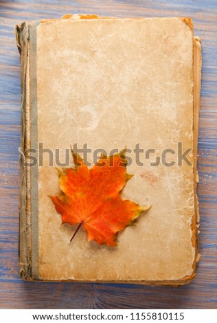 Old vintage books on wooden table with autumn leafs.