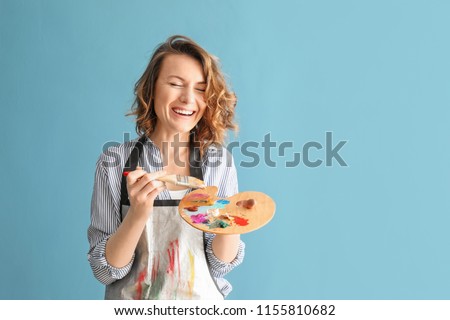 Female artist with brush and paint palette on color background Royalty-Free Stock Photo #1155810682