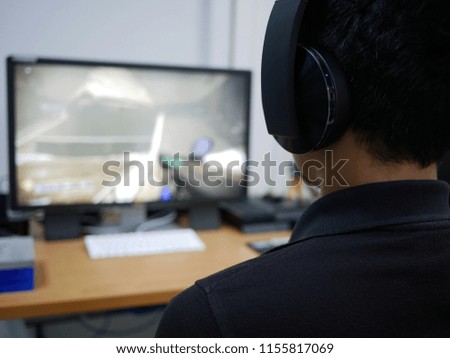 blurred of man playing video games online using headphones.