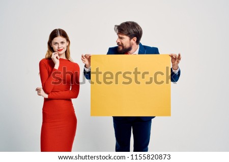 the man is looking at a woman in a red dress and is holding a large yellow leaf                              