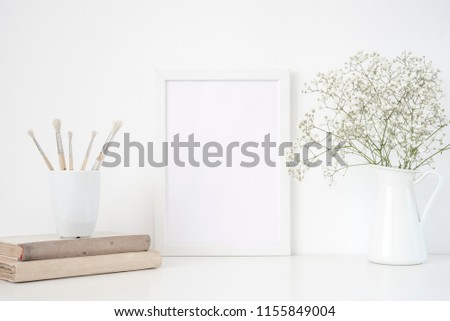 White frame mockup A4 in interior. Frame mock up background for poster or photo frame for social media, lettering, art and design. Indoor, frame on table with flowers in jug and vintage books. Summer