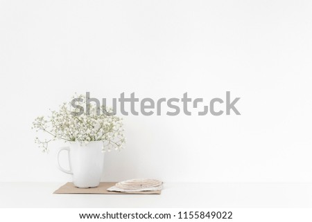 Background with stationary, seashells, bouquet of white flowers in mug on white wall background, tender soft home decor. Copy space for text. Empty space for lettering. Good buy summer