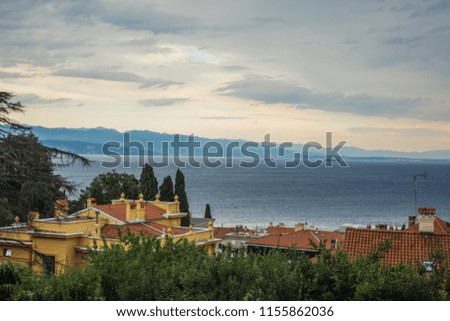 soft focus small houses shingles red roofs city view with nature scenery landscape of sea and mountain ridge horizon lane on background in evening summer sunset time before storm 