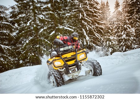 A man is riding an ATV in winter on the snow in his helmet. Royalty-Free Stock Photo #1155872302