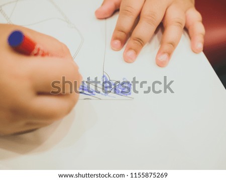 Close up hand of children is paiting on white paper