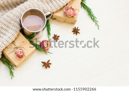 
Autumn composition. Hot chocolate, thujas, cinnamon, roses, gifts, scarf on a light wood background. Flat lay, top view, copy space