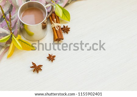 Autumn composition. Hot chocolate, autumn leaves, badon, cinnamon, scarf on a light wood background. Flat lay, top view, copy space